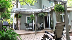 A covered patio area with a table and chairs, surrounded by potted plants and a tree. - Forest Hill Bed & Breakfast (Kitchener)