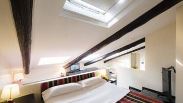 Une chambre d’hôtel équipée d’un lit, d’un bureau avec un ordinateur, d’une chaise, d’une télévision et d’une lucarne.
