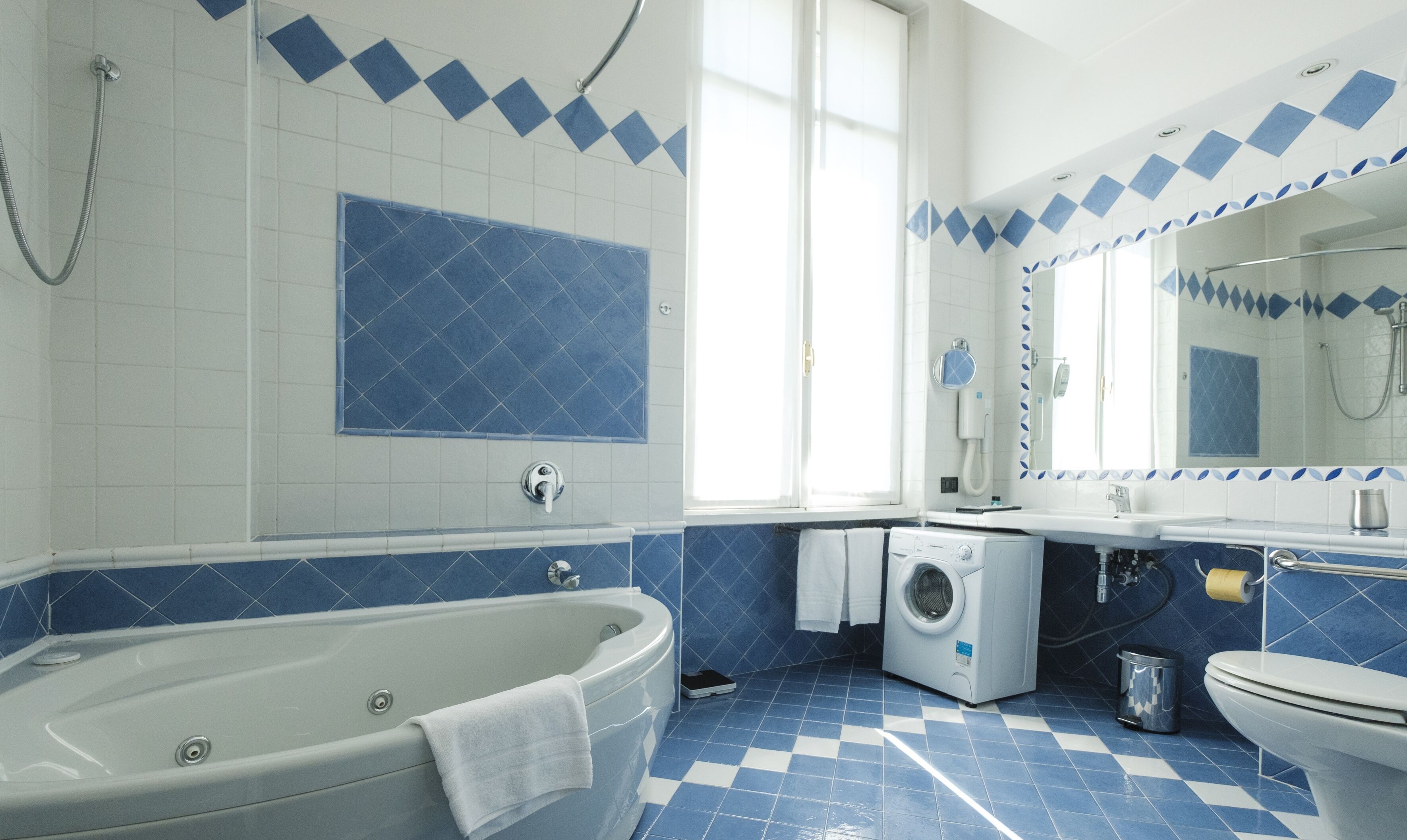 A bathroom with a bathtub, a washing machine, a toilet, and a sink.
