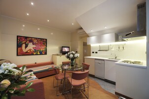 Una cocina moderna con armarios blancos, una mesa de comedor de vidrio y un sofá con cojines a rayas.