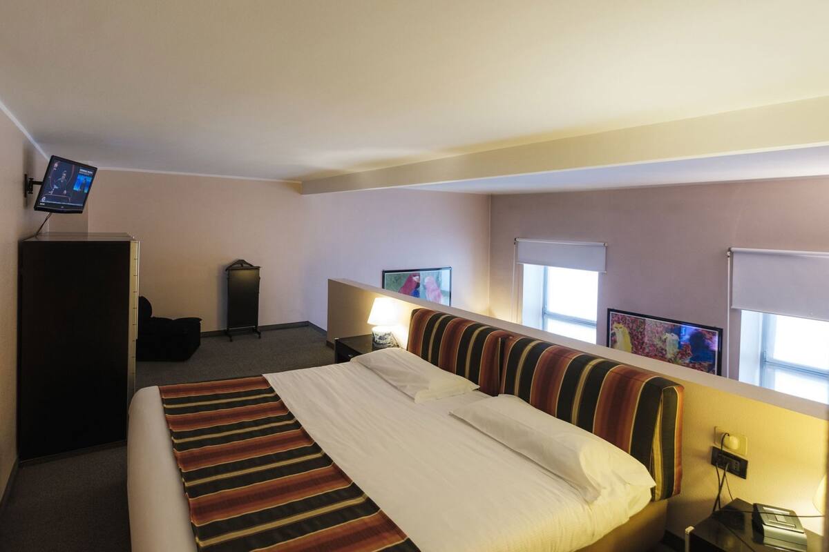 Una camera d'albergo con un letto, una scrivania, una televisione e una finestra.