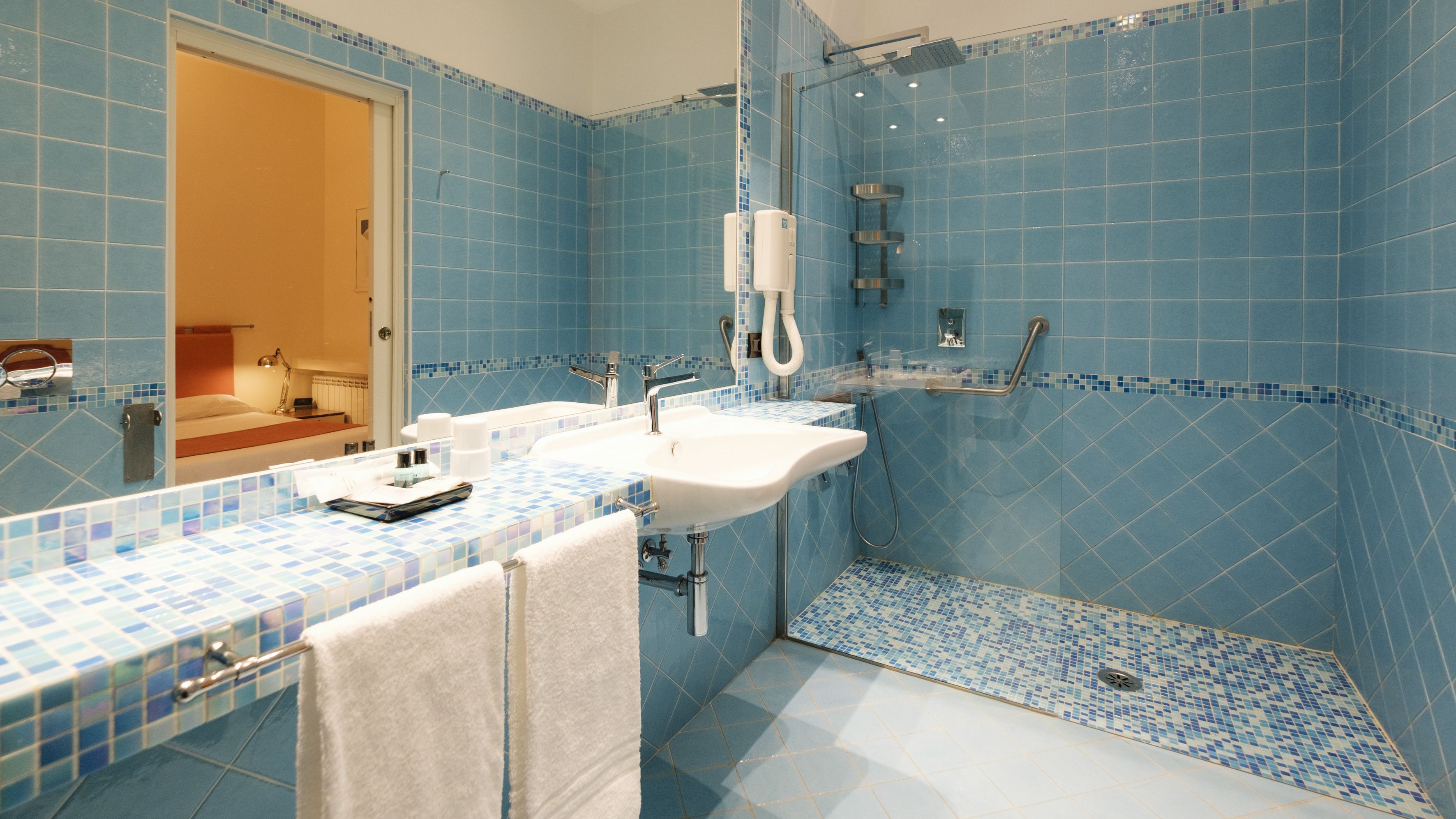 Un baño con azulejos azules, un lavabo blanco y una ducha.