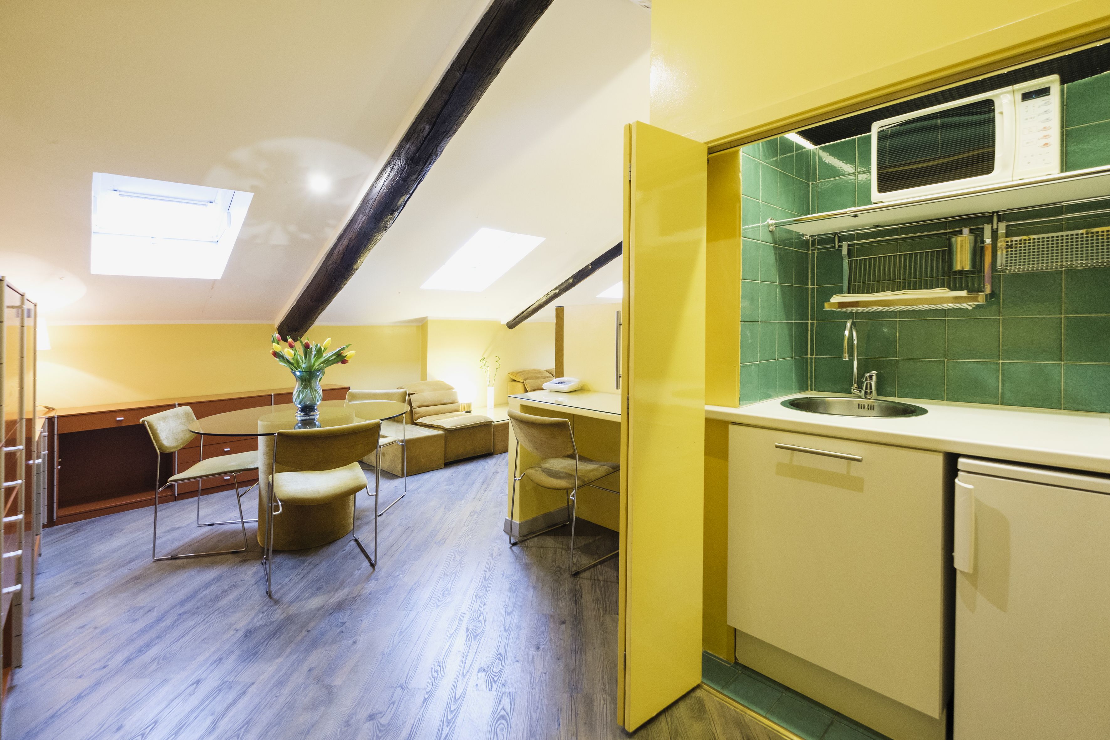 A compact kitchen with a microwave, sink, and a dining area with a table and chairs.