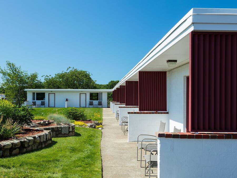 A row of white mobile homes with red shutters, each featuring a small porch and outdoor seating.