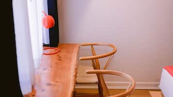 Una mesa de madera y dos sillas de madera en una habitación con pared blanca y ventana con cortinas.