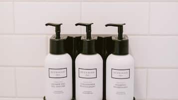 Three white bottles with black pumps on a white tiled wall.