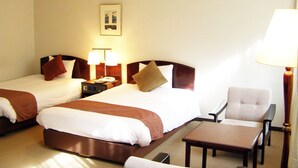A hotel room with two beds, a nightstand with lamps, a chair, and a table. - Hotel Marroad Karuizawa (Karuizawa)