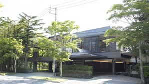 A modern building with a covered entrance, surrounded by trees and a stone pathway. - Hotel Marroad Karuizawa (Karuizawa)