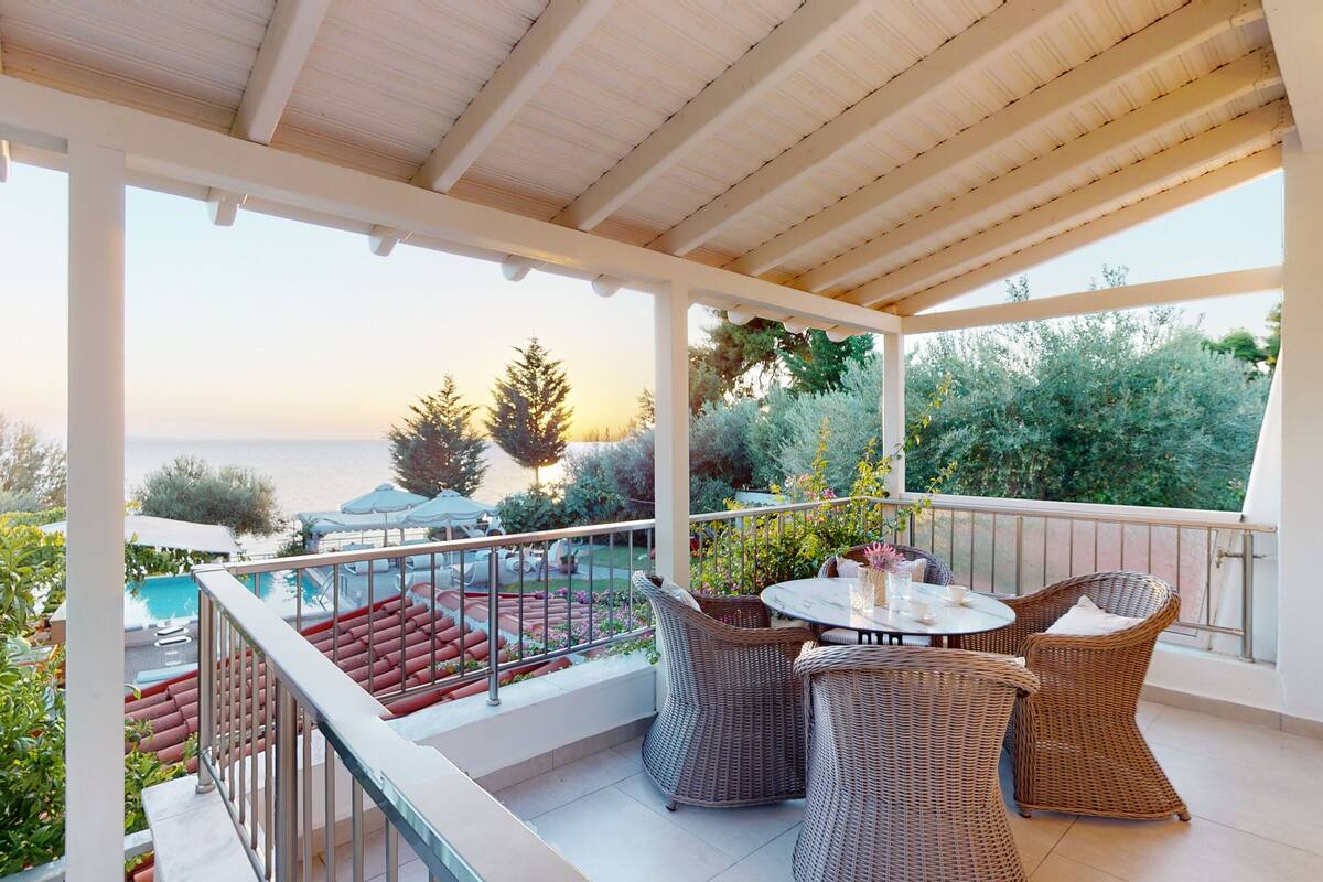 A covered outdoor area with wicker furniture, a pool, and a view of the sea.