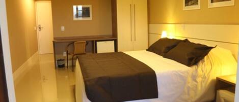 Una habitación de hotel con una cama, mesita de noche y un escritorio con silla.