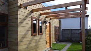A house with a wooden exterior, a front door, and a small front yard with a paved walkway.