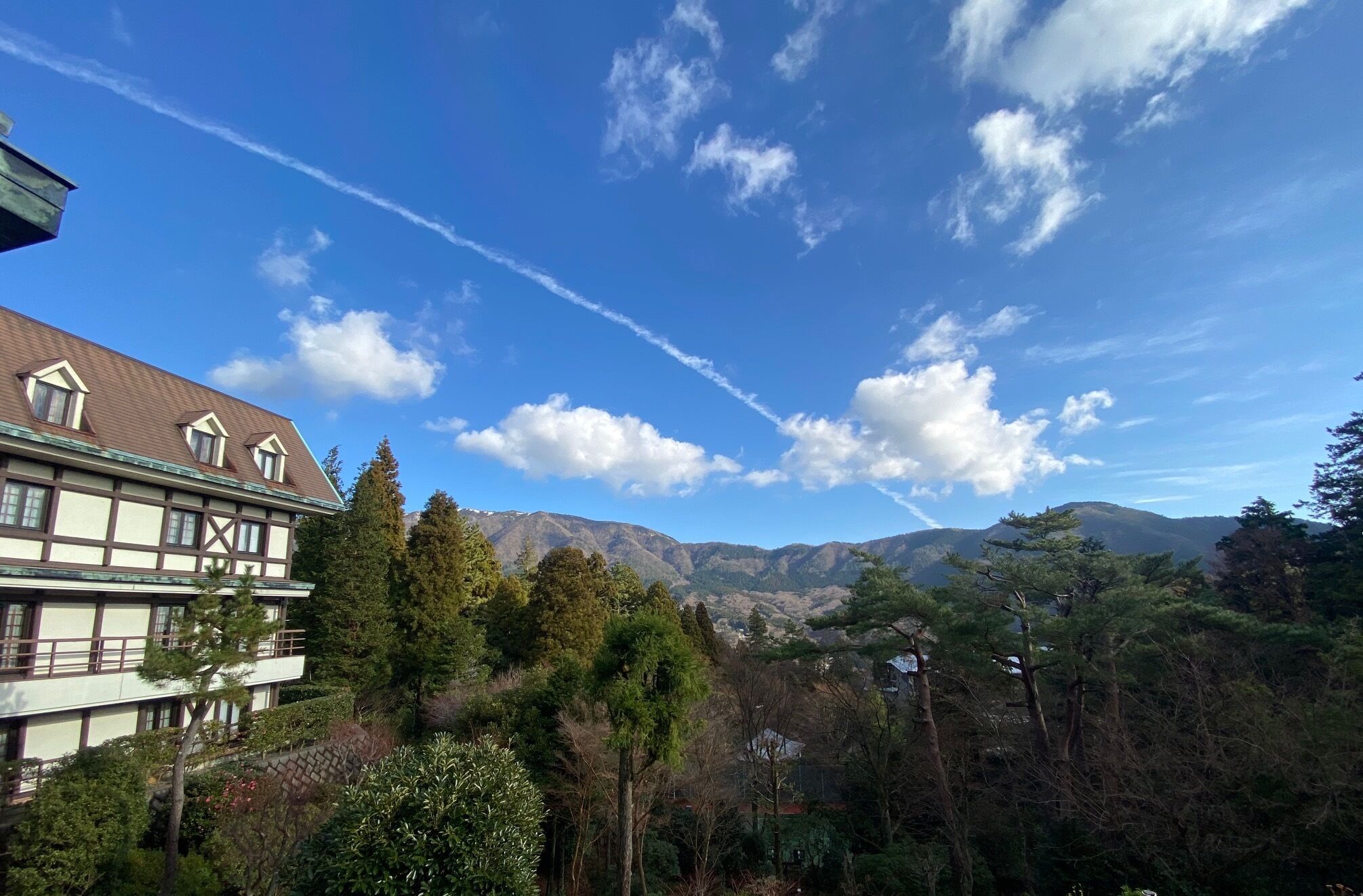 A building with a traditional architectural style, a mountainous landscape in the background, and a clear sky.
