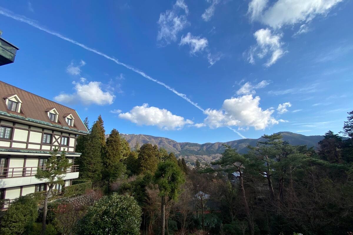 A building with a traditional architectural style, a mountainous landscape in the background, and a clear sky.