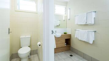 A small, clean bathroom with a toilet, sink, and mirror.