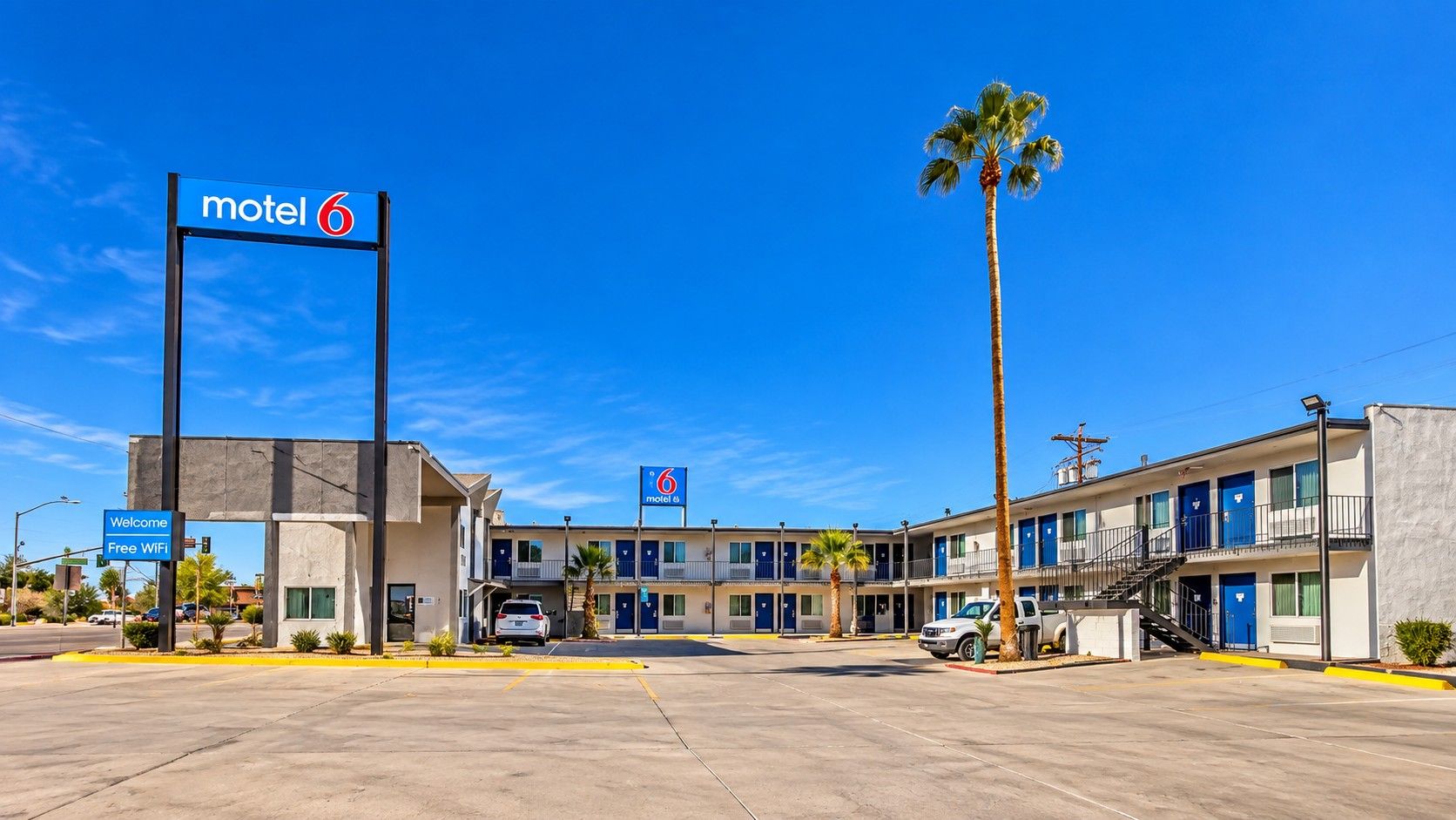 A motel with a signboard, a parking lot, and a clear blue sky.