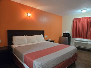 A hotel room with a large bed, a nightstand, a microwave, a refrigerator, and a window with curtains. - Motel 6 Blythe, CA - South (Blythe)