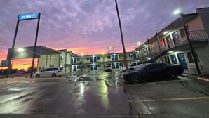 Un motel con varias habitaciones, un estacionamiento y un cielo al atardecer.