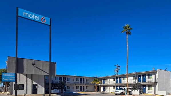 A motel with a 'Welcome Free WIFI' sign, a palm tree, and a clear blue sky. - Motel 6 Blythe, CA - South (Blythe)