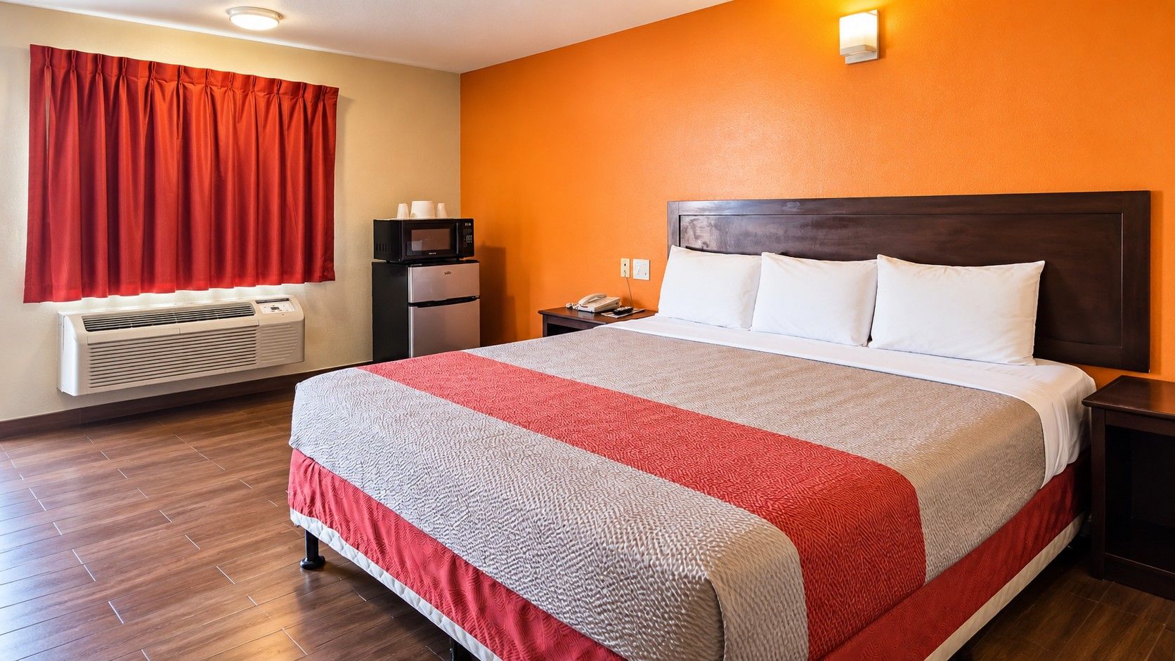 Ein Hotelzimmer mit einem Bett, einem Heizgerät, einer Mikrowelle und einem Telefon auf einem Nachttisch.