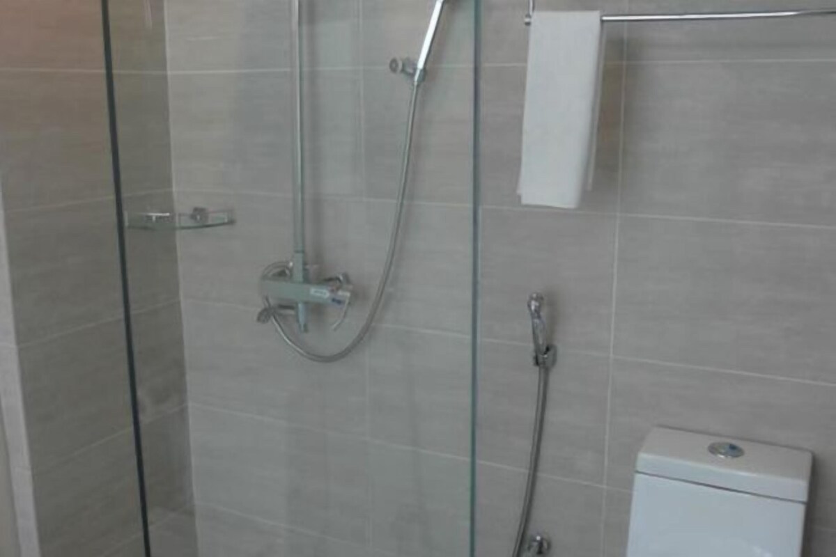 A glass-enclosed shower area with a handheld showerhead and a wall-mounted faucet.