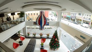 A modern hotel lobby with a glass railing, a Christmas tree, and a view of the street below. - Hotel French Ipoh (Ipoh)
