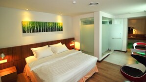 A hotel room with a large bed, bedside tables with lamps, a painting on the wall, a shower area, and a seating area with chairs. - Hotel French Ipoh (Ipoh)