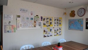A conference room with a wooden table, white chairs, and a bulletin board with various papers and photos. - Submarine Guest House Central Market - Hostel (Kuala Lumpur)