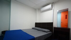 A single bed with a blue and gray bedspread, a black headboard, and an air conditioning unit above it. - Submarine Guest House Central Market - Hostel (Kuala Lumpur)