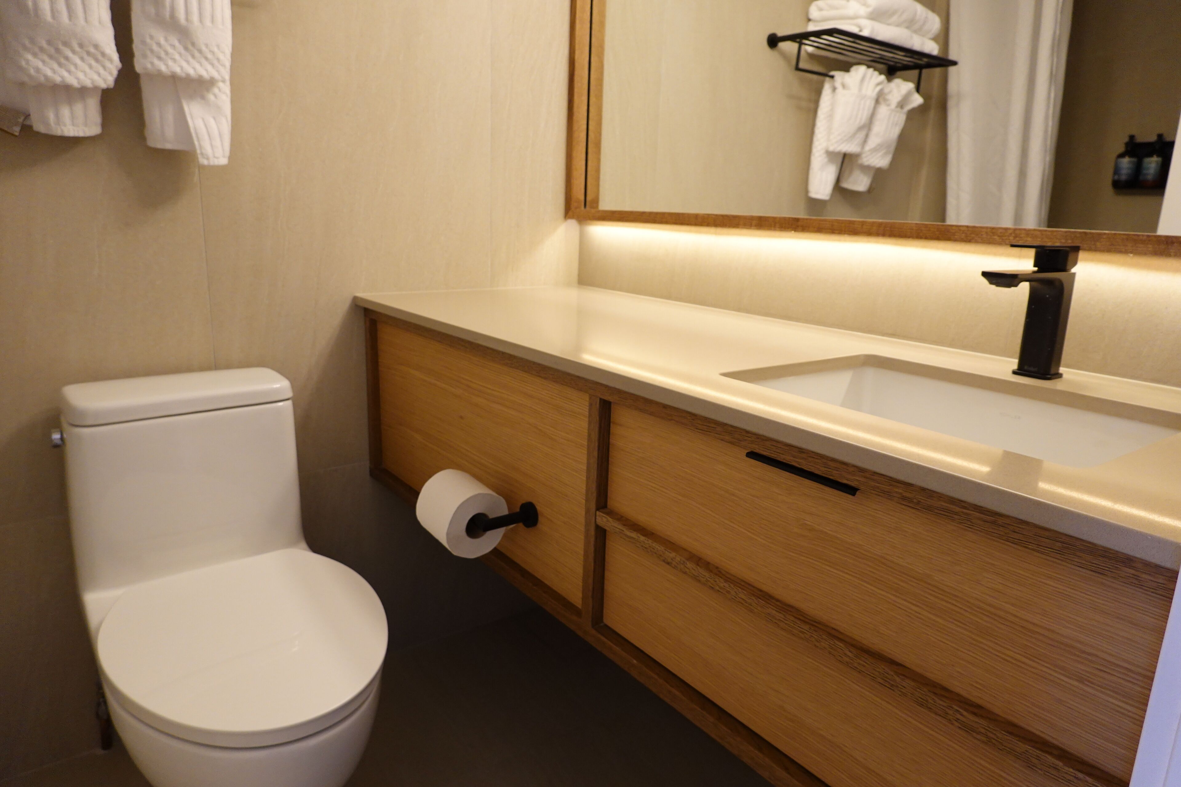 Un bagno moderno con il water, un lavandino e uno specchio.