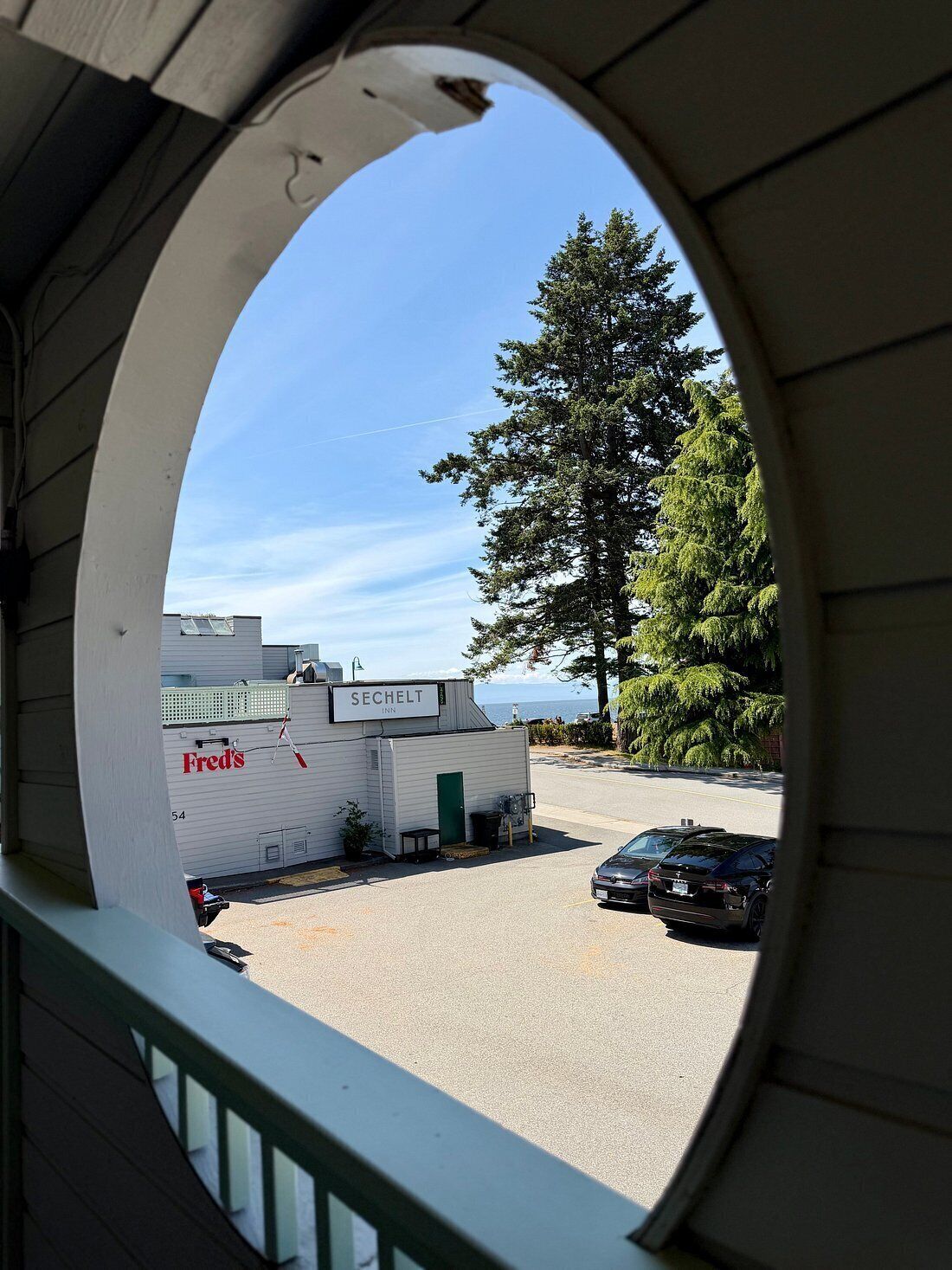 Vista a través de una ventana de un edificio con un letrero que dice 'SECHELT INN' y 'Fred's' en la fachada.