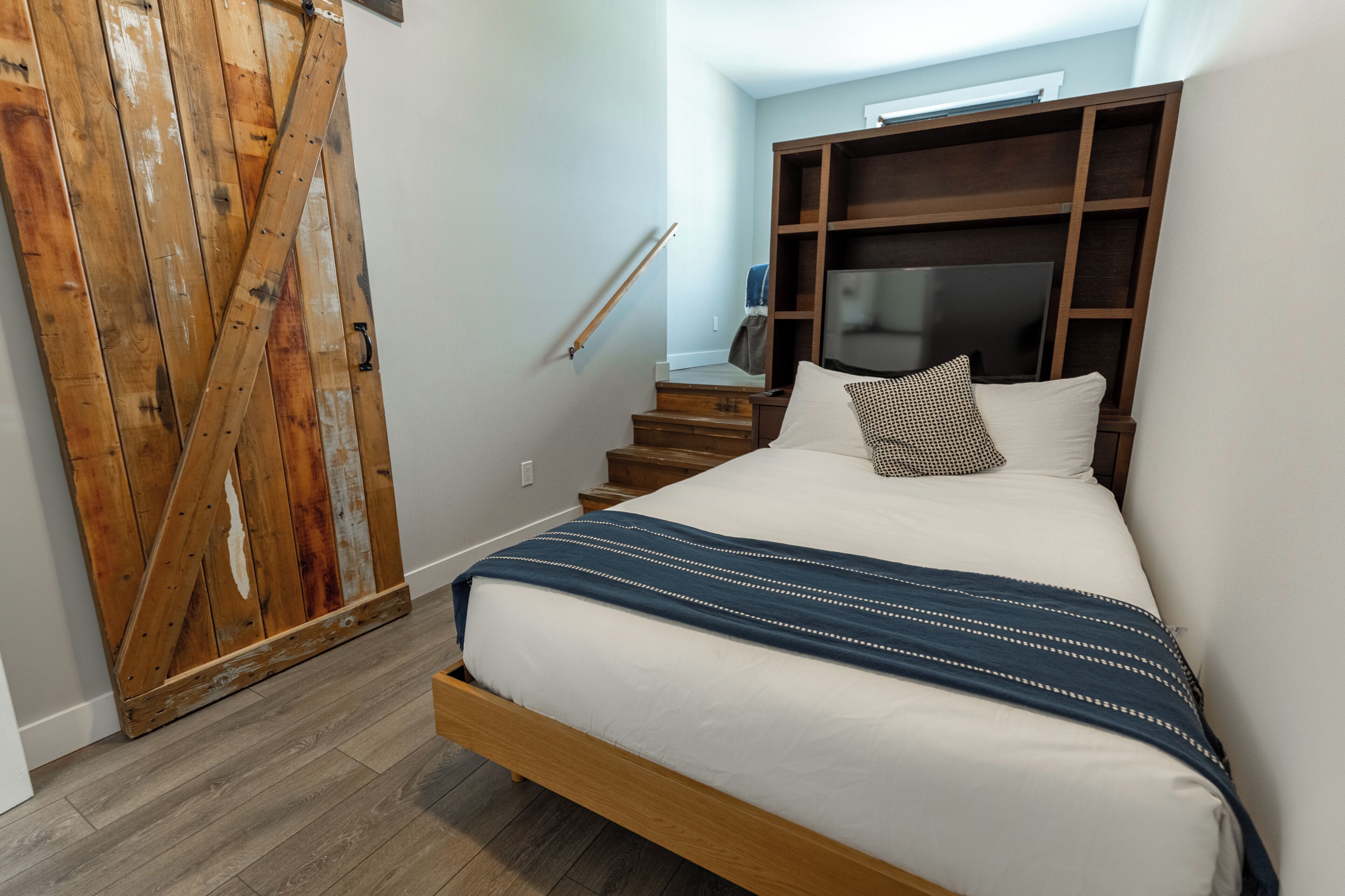Un dormitorio con una cama de madera, un televisor y un armario.