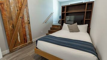 Un dormitorio con una cama de madera, un televisor y un armario.