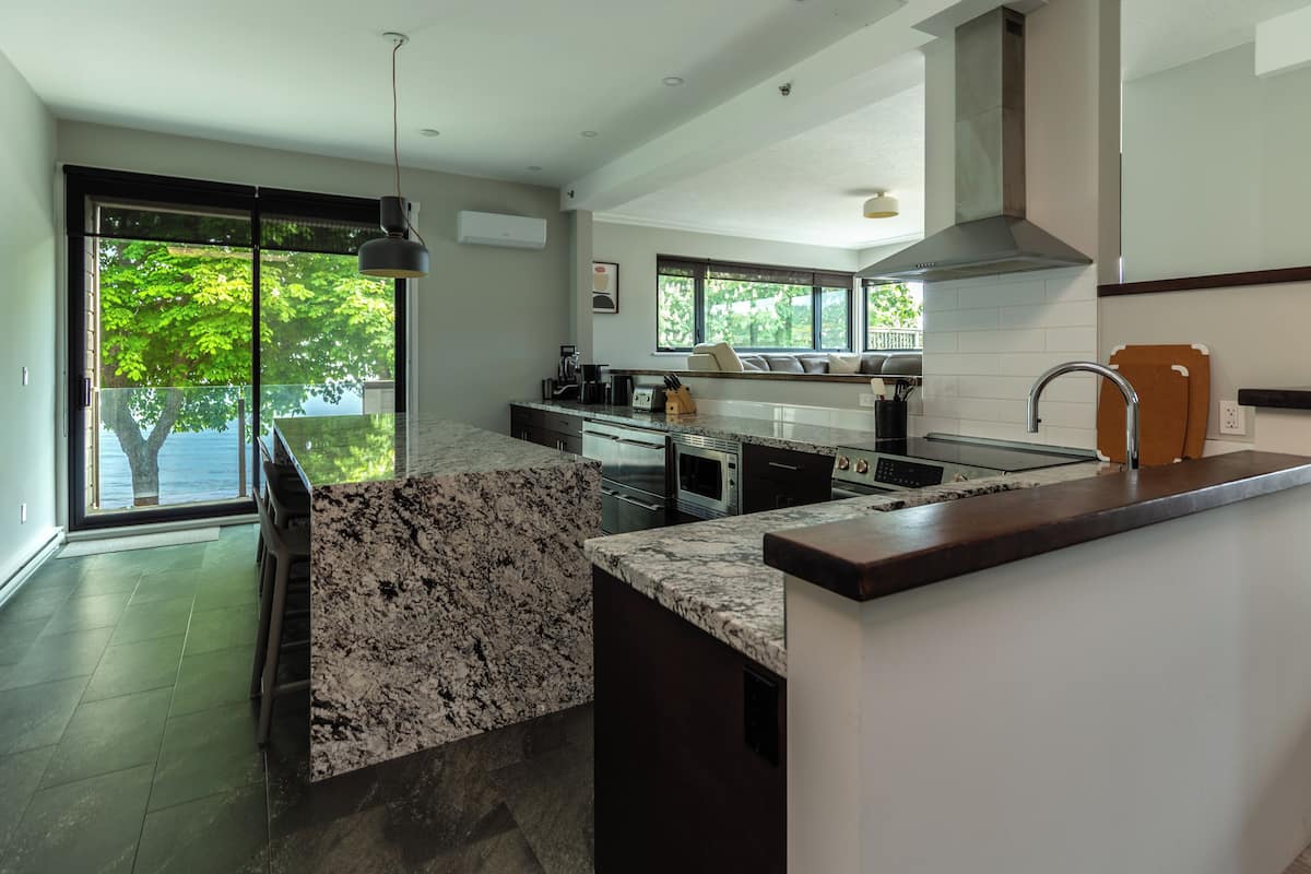 A modern kitchen with a large island, built-in appliances, and a view of the outdoors.