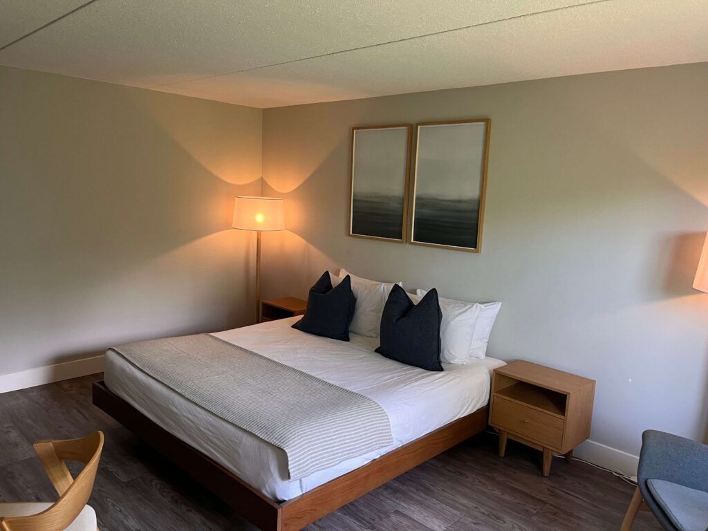 A bedroom with a large bed, bedside lamps, a wooden nightstand, and a chair.