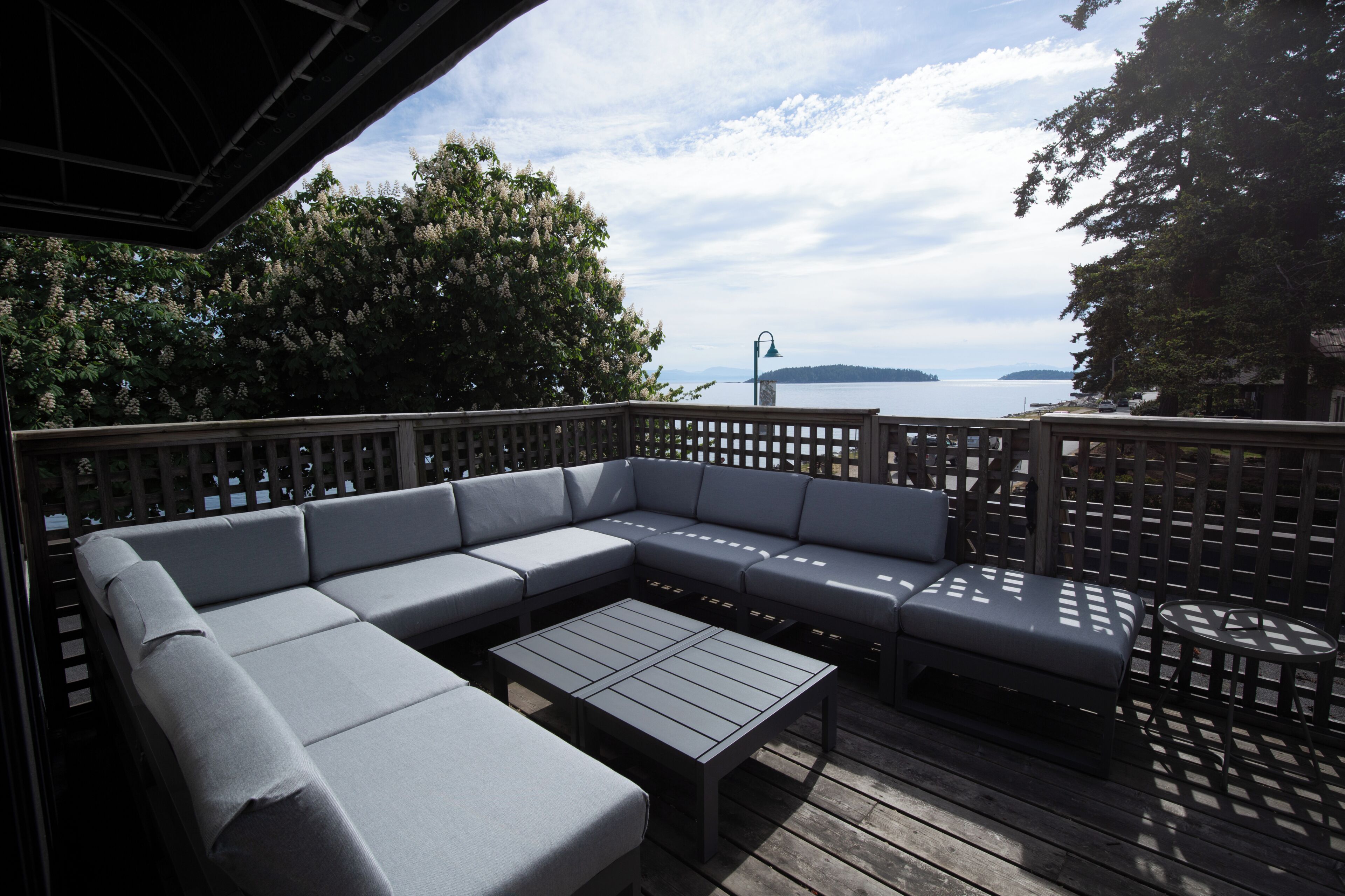 Une terrasse dotée d’un canapé modulable, d’une petite table et offrant une vue sur l’eau.