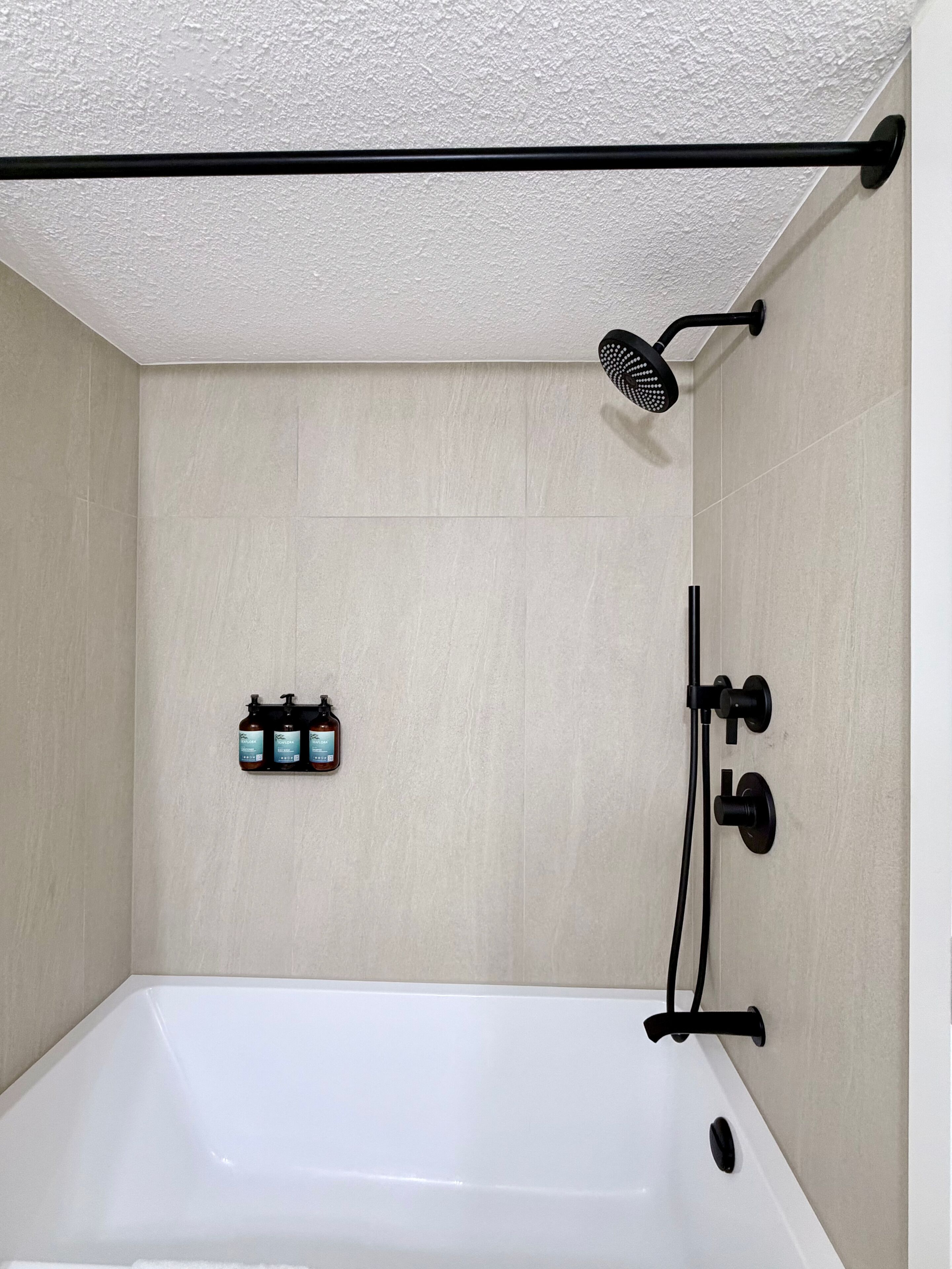 Un baño con bañera, ducha de mano y dispensador de jabón de pared.