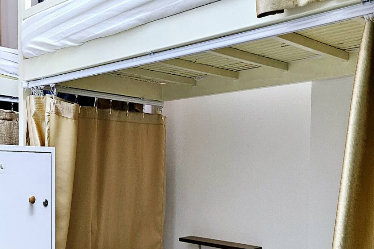 Uma cama beliche com armário de armazenamento, mesa de cabeceira e cortina.