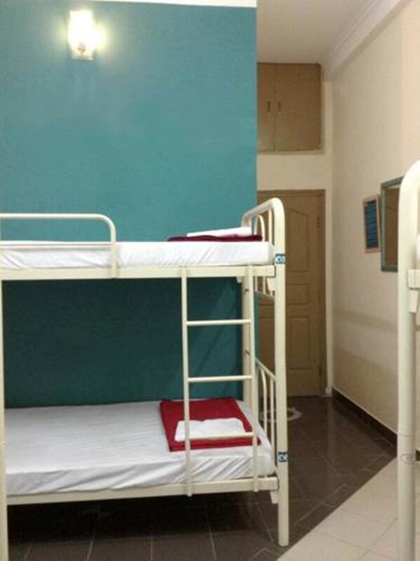 Habitación con literas, una pared verde azulado, una puerta blanca y un ventanal pequeño.