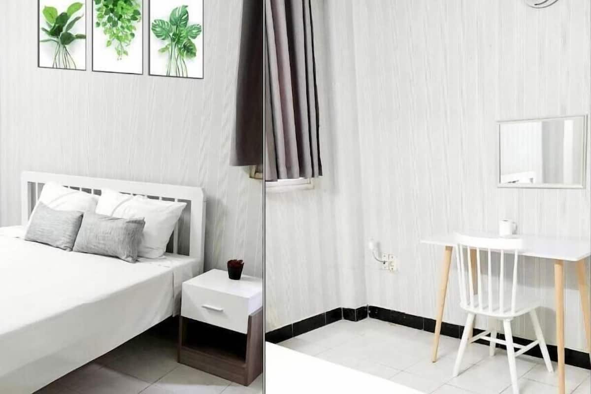 Quarto moderno com cama, mesa de cabeceira e pequena escrivaninha com cadeira.