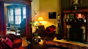 A traditional living room with a fireplace, a red sofa, a table, and a lamp. - B&B La Marquise de Bassano / B&B Québec (Québec City)