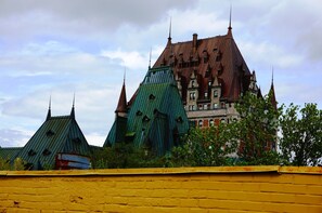Um edifício histórico com várias torres e um telhado verde, cercado por um muro amarelo.