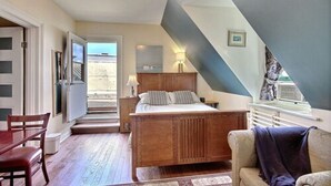 A bedroom with a wooden bed, a nightstand, a chair, and a window with a view. - B&B La Marquise de Bassano / B&B Québec (Québec City)