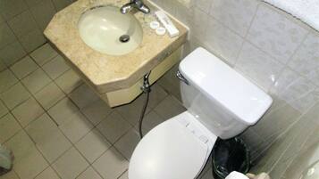 Un baño con lavamanos, inodoro y un cubo de basura.