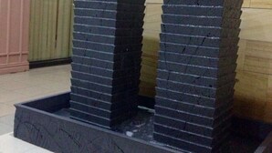 Two stacked black water features in a tiled area with a wooden wall and a glass door in the background. - Grand City Hotel (Cagayan de Oro)