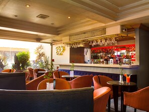 A bar area with orange chairs, a bar counter with bottles, and a decorative wall with a logo. - Grand City Hotel (Cagayan de Oro)