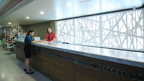 A reception desk with a marble counter, a patterned wall, and a tiled floor. - Grand City Hotel (Cagayan de Oro)