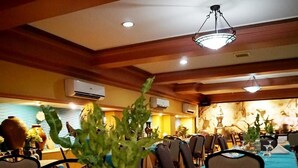 A dining table set with breakfast items including toast, eggs, and fruit, in a restaurant with wooden ceiling beams and a chandelier. - Grand City Hotel (Cagayan de Oro)