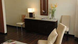 A hotel reception area with a desk, a chair, a lamp, a mirror, and a vase with flowers. - Manila Manor Hotel (Manila)