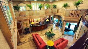 A spacious lobby with a high ceiling, a central seating area with red sofas, a bar area, and a balcony with plants. - Manila Manor Hotel (Manila)