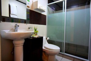 A bathroom with a pedestal sink, a toilet, and a glass shower enclosure. - Manila Manor Hotel (Manila)